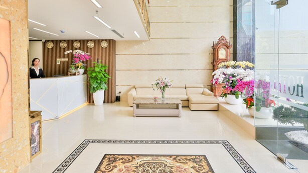 A hotel lobby with a reception desk, a sofa, a coffee table, and decorative plants. - Prague Saigon Airport Hotel (Ho Chi Minh City)