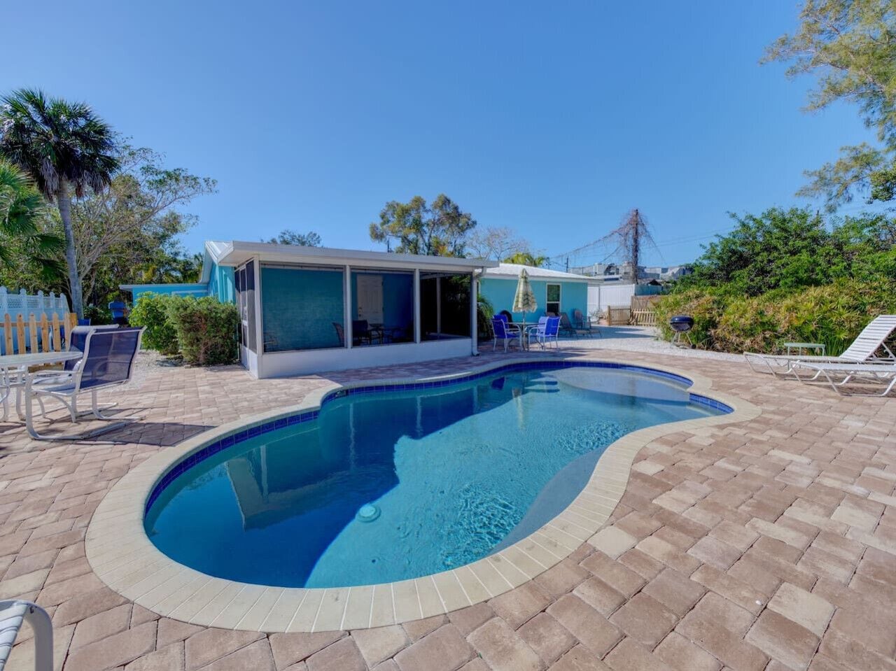 A swimming pool with a curved edge, surrounded by a brick patio.