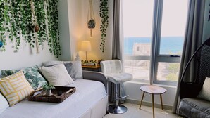 Una sala de estar moderna con un sofá, una silla, una mesita y vistas al mar.
