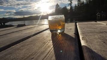 A glass of amber liquid on a wooden surface with a sunset in the background.