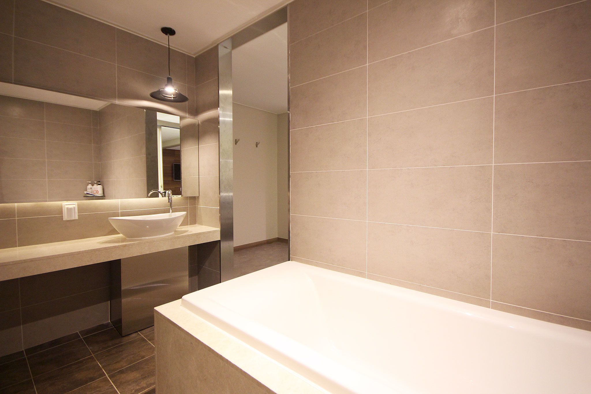 Ein modernes Badezimmer mit einer großzügigen Badewanne, einem Aufsatzwaschbecken und einem Spiegel.