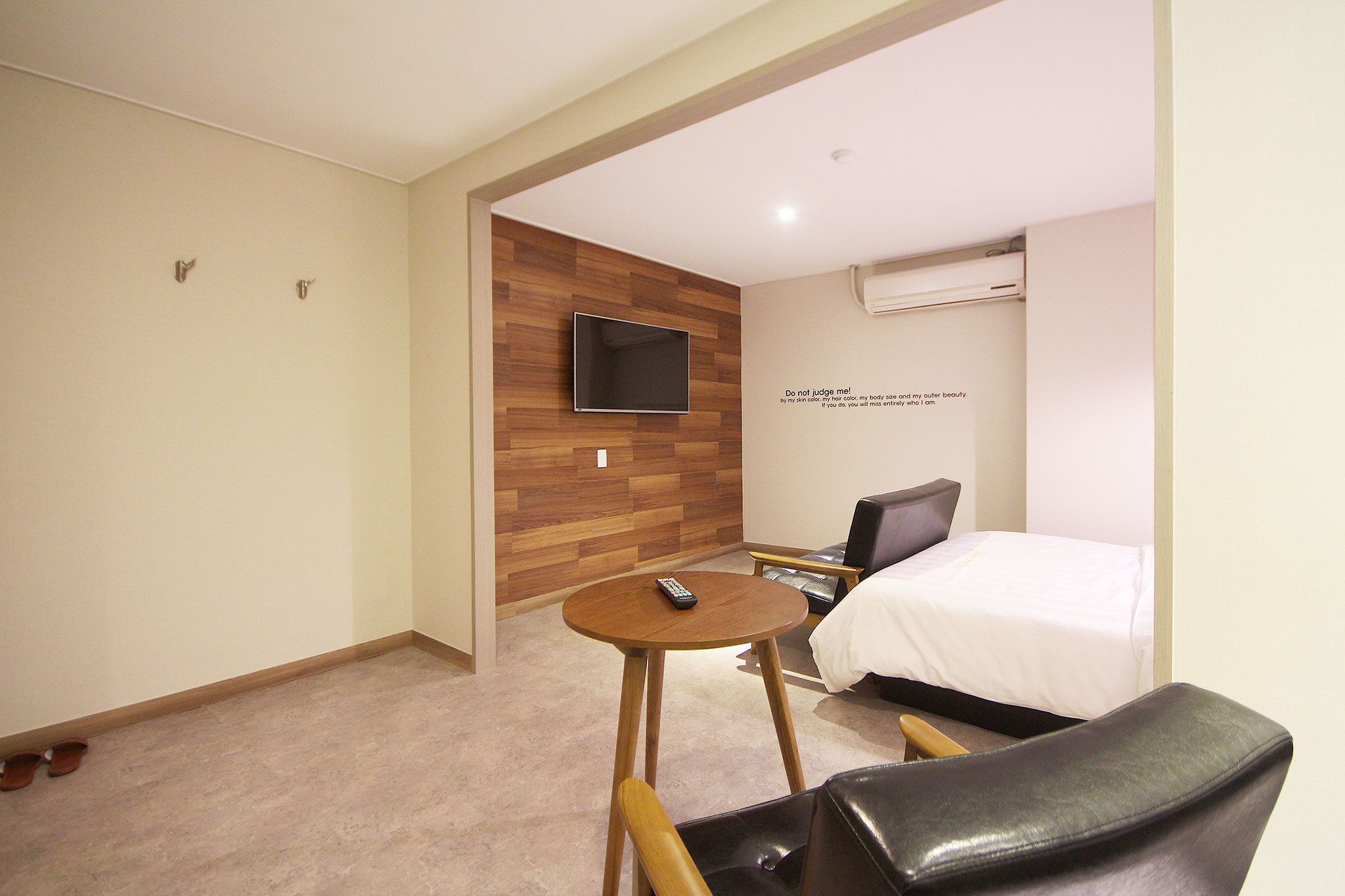 Quarto de hotel com cama, televisão na parede, mesa redonda pequena e uma cadeira.