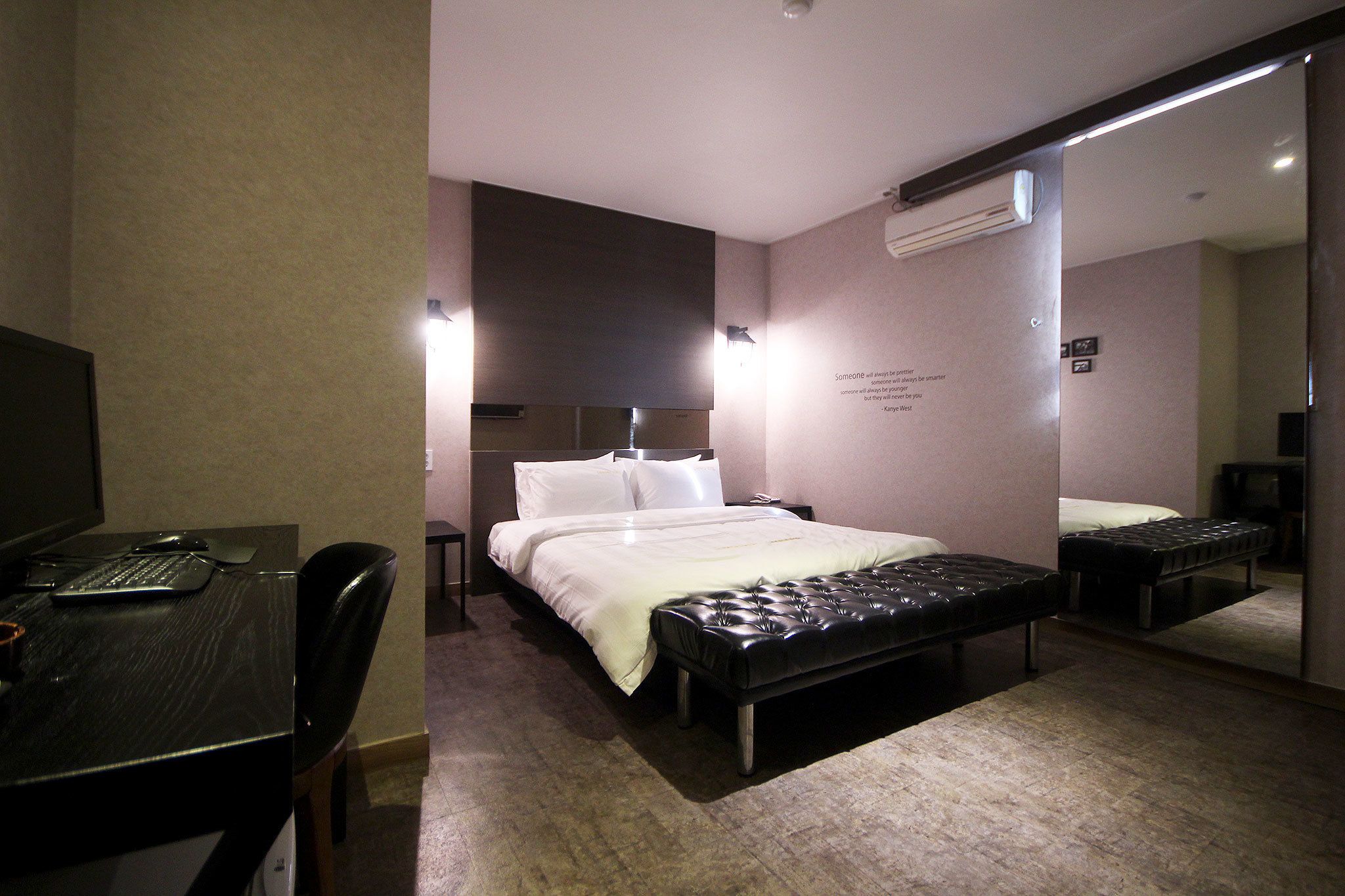 Habitación de hotel con cama, escritorio, silla y banco.