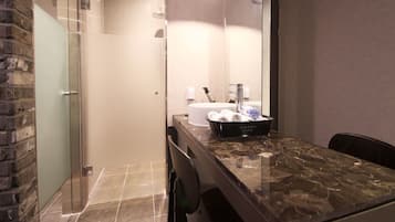 A modern bathroom with a glass shower enclosure, a marble countertop, and a sink with a towel rack.