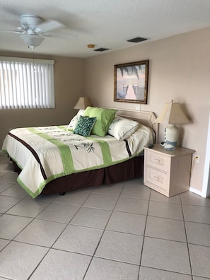 Comfortable room with a neatly made bed, ceiling fan, and a nightstand with a lamp.