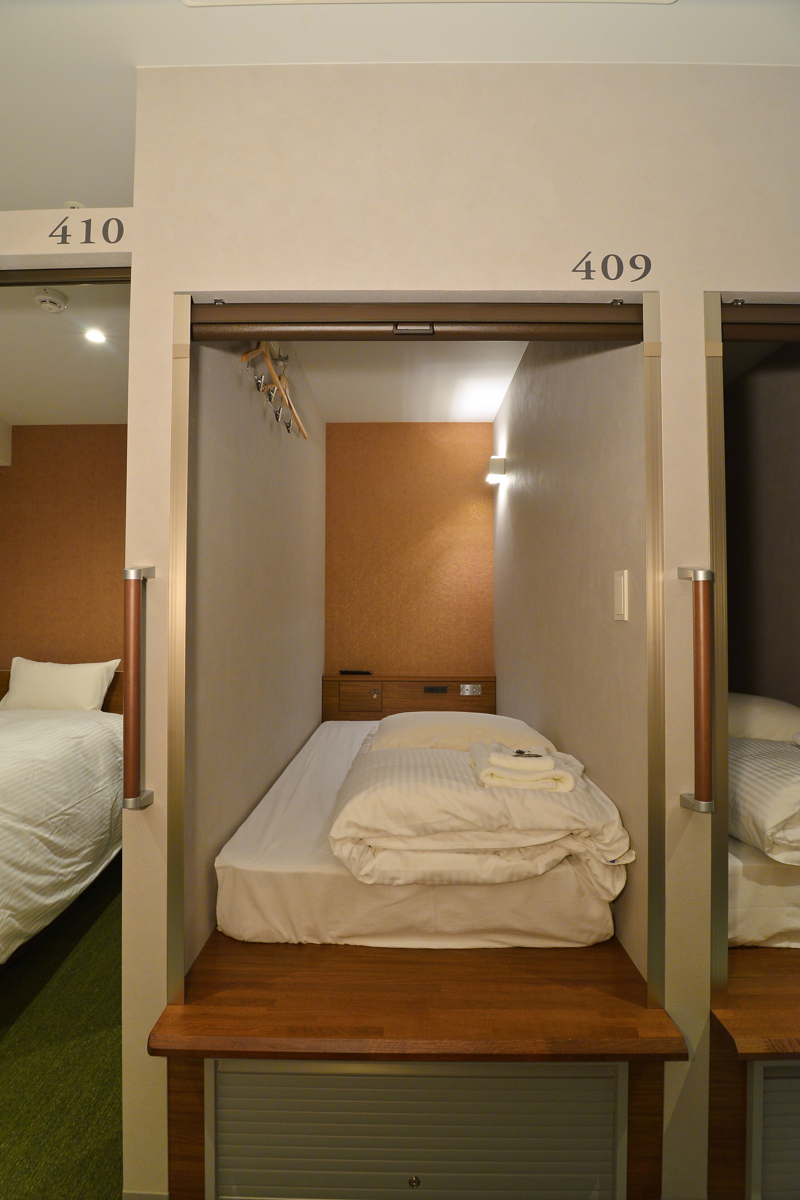 A hotel room with a single bed, a wooden headboard, a small bedside table, and a wall-mounted light.