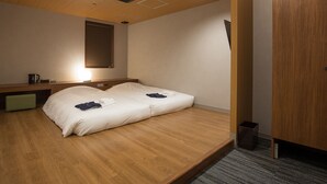 Ein modernes Hotelzimmer mit Holzboden, einem Bett mit weißer Bettwäsche, einem Nachttisch mit Lampe und einem großen Spiegel an der Wand.