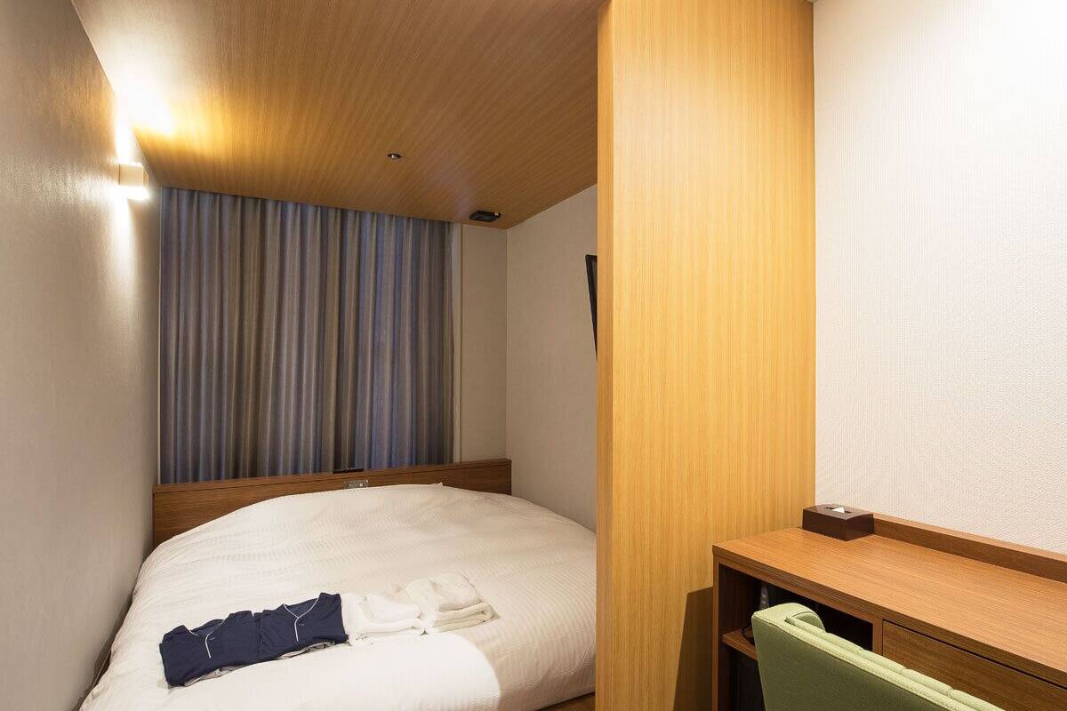 Une chambre d’hôtel avec un lit, un bureau et une chaise.