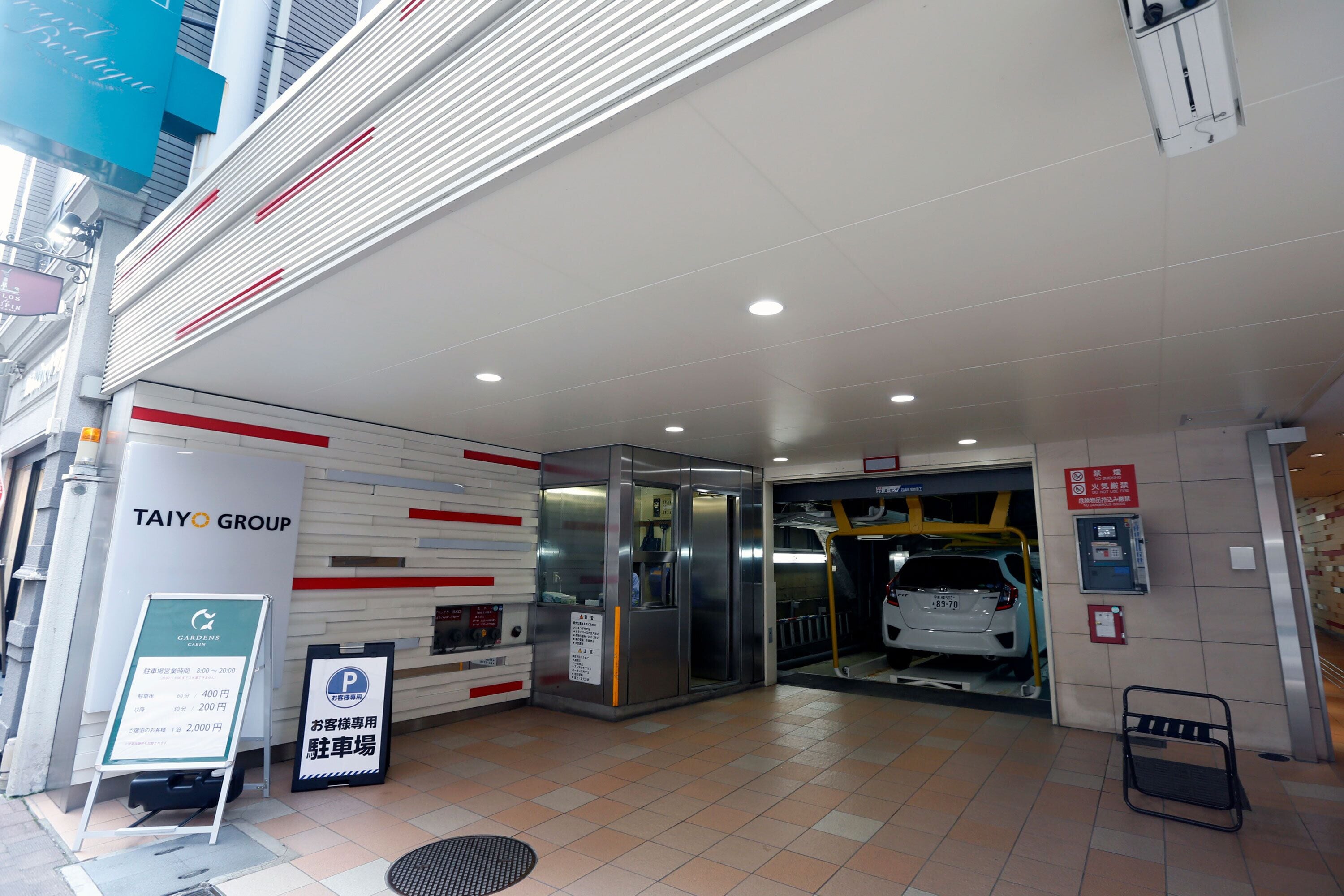 A modern building entrance with a sign for Taiyo Group, a parking sign, and a fire extinguisher.