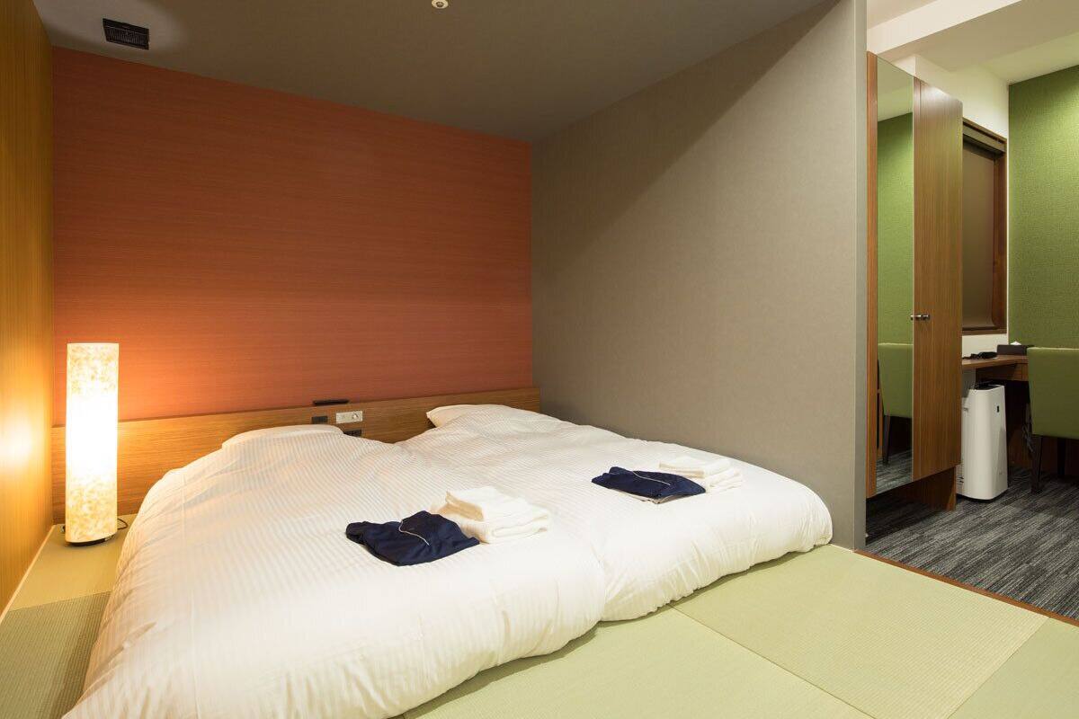 Une chambre d’hôtel comprenant un lit, une table de chevet, une lampe et un bureau avec une chaise.
