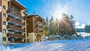 Ein mehrstöckiges Hotel mit Balkonen, eine verschneite Landschaft und ein klarer Himmel.