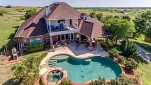 Une maison à deux étages avec un grand jardin, une piscine et un jacuzzi.