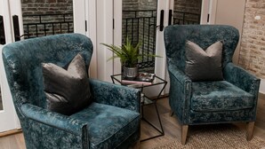 Una habitación con dos sillones color turquesa, una mesita con una planta y una alfombra blanca.