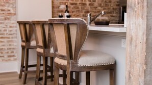 Una cocina con pared de ladrillo, taburetes de madera y luminarias colgantes.