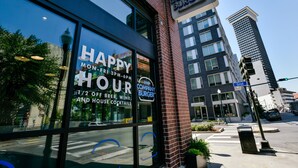 Un restaurante con un amplio ventanal que muestra sus ofertas y horarios de happy hour.