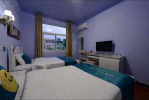 Une chambre d’hôtel avec deux lits, un bureau, une télévision et une fenêtre avec des rideaux.