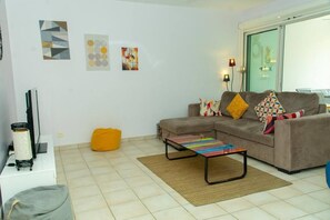 A living room with a sofa, colorful cushions, a bean bag, and a coffee table.