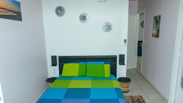 A room with a bed, two bedside tables, a wall with decorative plates, and a door leading to another room.