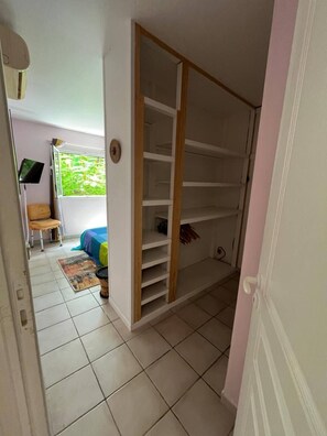 Una habitación con armario corredero, cama con colcha colorida, televisor y ventana con vista a zonas verdes.