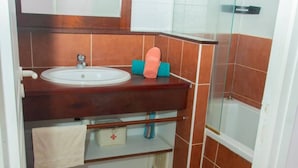 A bathroom with a sink, mirror, towel rack, and shower area.