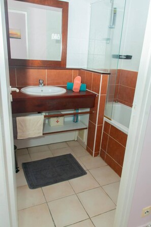 Un bagno con lavandino, specchio, porta asciugamani e zona doccia.