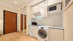 Une cuisine compacte équipée d’un lave-linge, d’un four à micro-ondes et d’une machine à café.