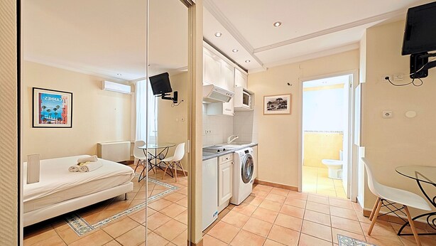 Une chambre d’hôtel compacte comprenant un lit, un petit coin repas, un lave-linge et un téléviseur.