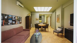 A modern living room with a sofa, a dining table with chairs, a coffee table with a vase, and a TV. - NEW APARTMENT - Central Athens - Kolonaki, luxury modern flat.  (Athina)