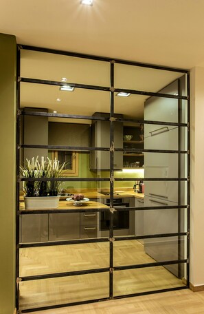 Une cuisine moderne avec un parquet en bois disposé en chevrons, un îlot central intégré et une cloison en verre.