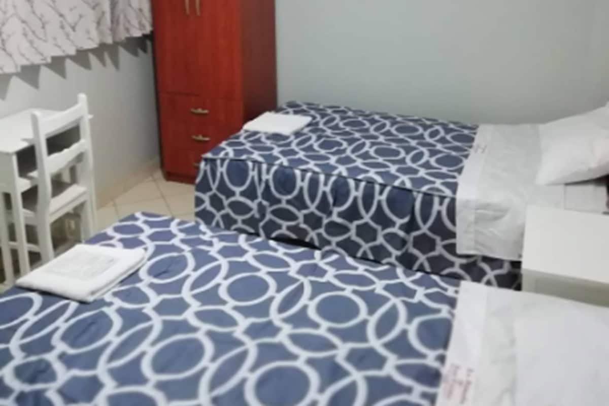 Un dormitorio con dos camas, un armario y una silla.