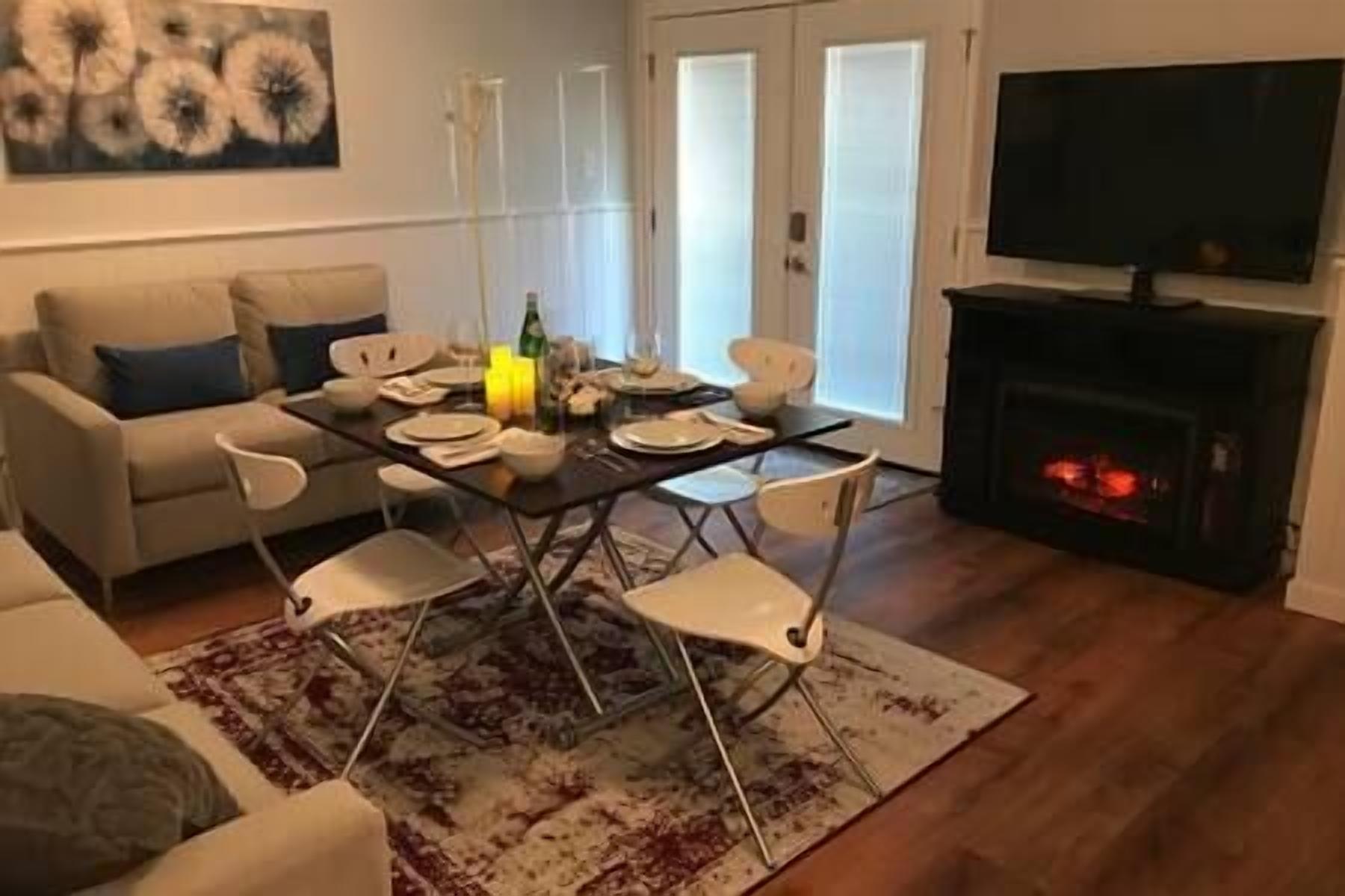Una sala de estar con sofá, mesa de comedor, sillas, chimenea y televisor.