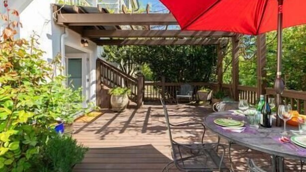 A wooden deck with a red umbrella, outdoor seating, and potted plants. - Cozy Laurelhurst 1 Bedroom Apt Near Children’s Hospital, UW, Husky Stadium, UWMC (Seattle)