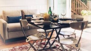 A dining area with a table set for four, a sofa, and a staircase leading to an outdoor area. - Cozy Laurelhurst 1 Bedroom Apt Near Children’s Hospital, UW, Husky Stadium, UWMC (Seattle)