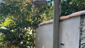 Un muro de concreto con una puerta metálica, un poste de madera y una estructura metálica en la parte superior.