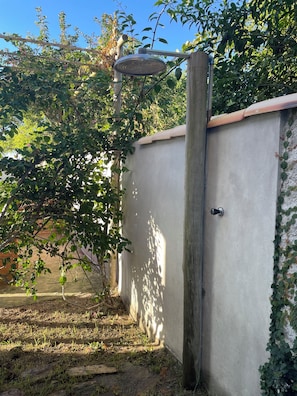 A concrete wall with a metal door, a wooden post, and a metal structure above. - Suites in Buzios with master barbecue (Armação dos Búzios)