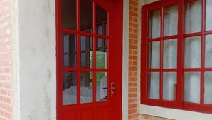 Una puerta roja con ventanal, ubicada en un edificio de ladrillo.