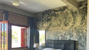 Un dormitorio con una cama grande, un sofá, una lámpara y vistas al exterior.