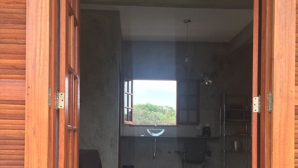 Una habitación con un ventanal amplio, un área de cocina y vistas al exterior.