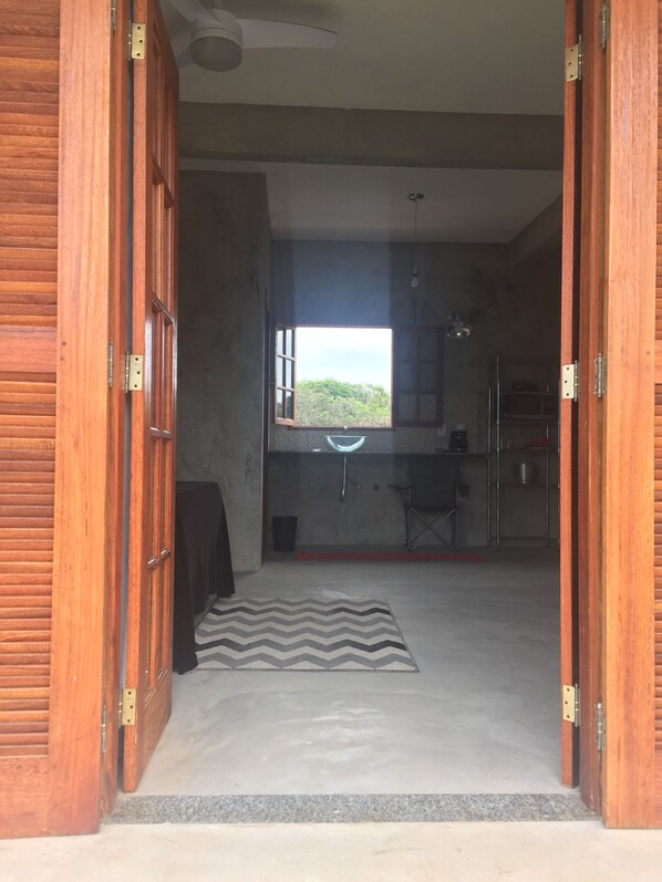 A room with a large window, a kitchen area, and a view of the outdoors. - Suites in Buzios with master barbecue (Armação dos Búzios)