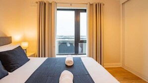 Une chambre d’hôtel avec un lit, une vue sur le balcon et une fenêtre avec des rideaux.