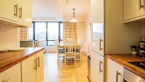 Une cuisine moderne avec des plans de travail en bois, des armoires blanches et un coin repas comprenant une table et des chaises.