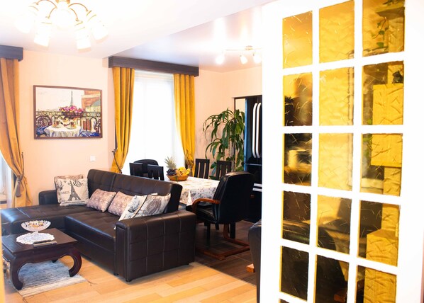 Un salon avec un canapé, une table à manger, des chaises et un tableau accroché au mur.