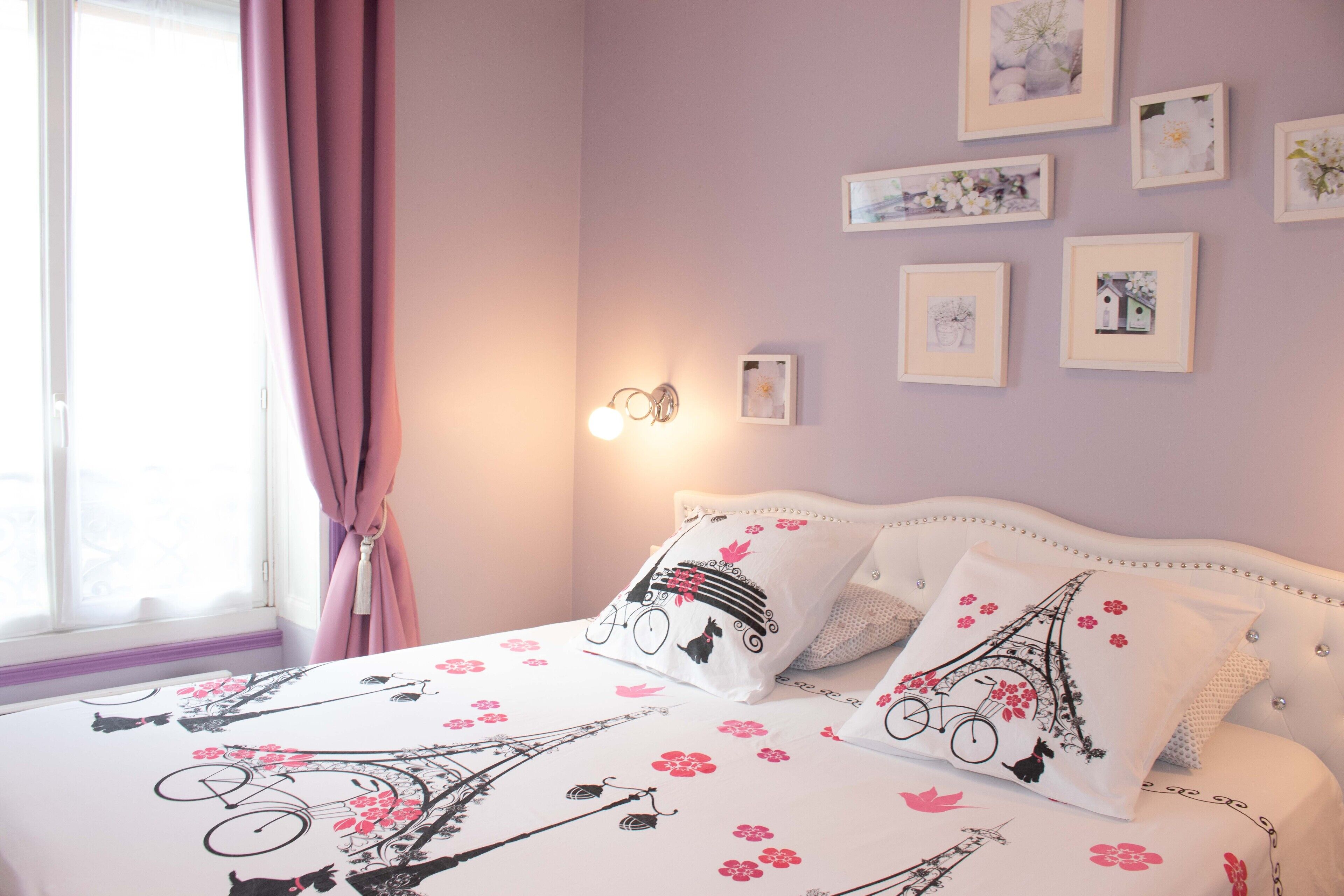 Une chambre à coucher avec un lit, des rideaux roses et des tableaux accrochés au mur.