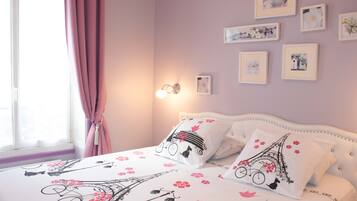 Une chambre à coucher avec un lit, des rideaux roses et des tableaux accrochés au mur.