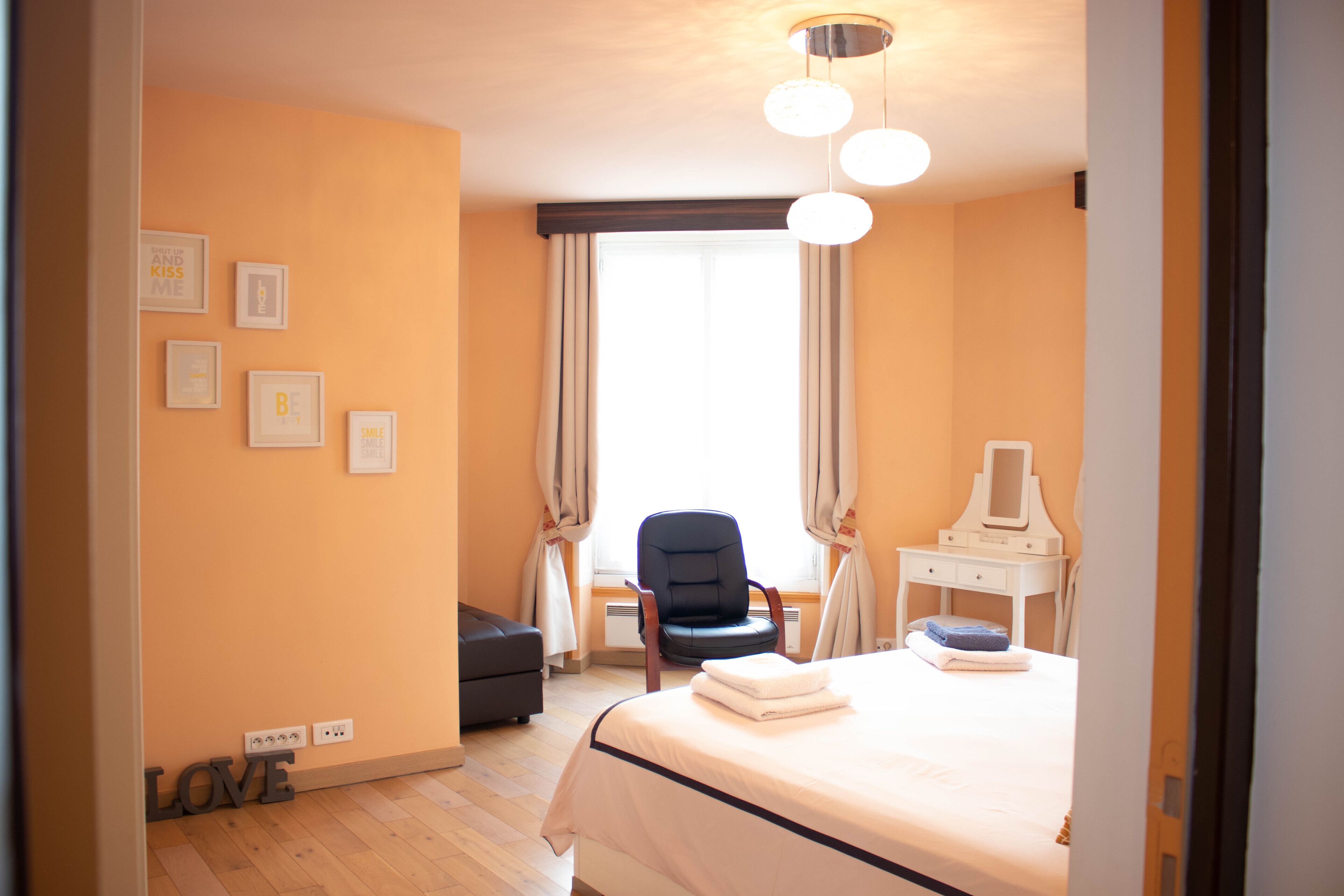 Habitación de hotel con cama, escritorio, silla y ventana con cortinas.