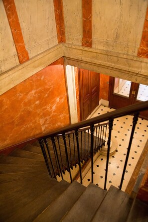 A staircase with a wooden handrail and a patterned floor.