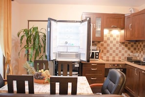 A compact kitchen with wooden cabinets, a built-in microwave, and a dining area with a table set for two.