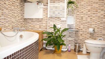 Une salle de bain avec une baignoire, des toilettes, un lavabo et une plante en pot.