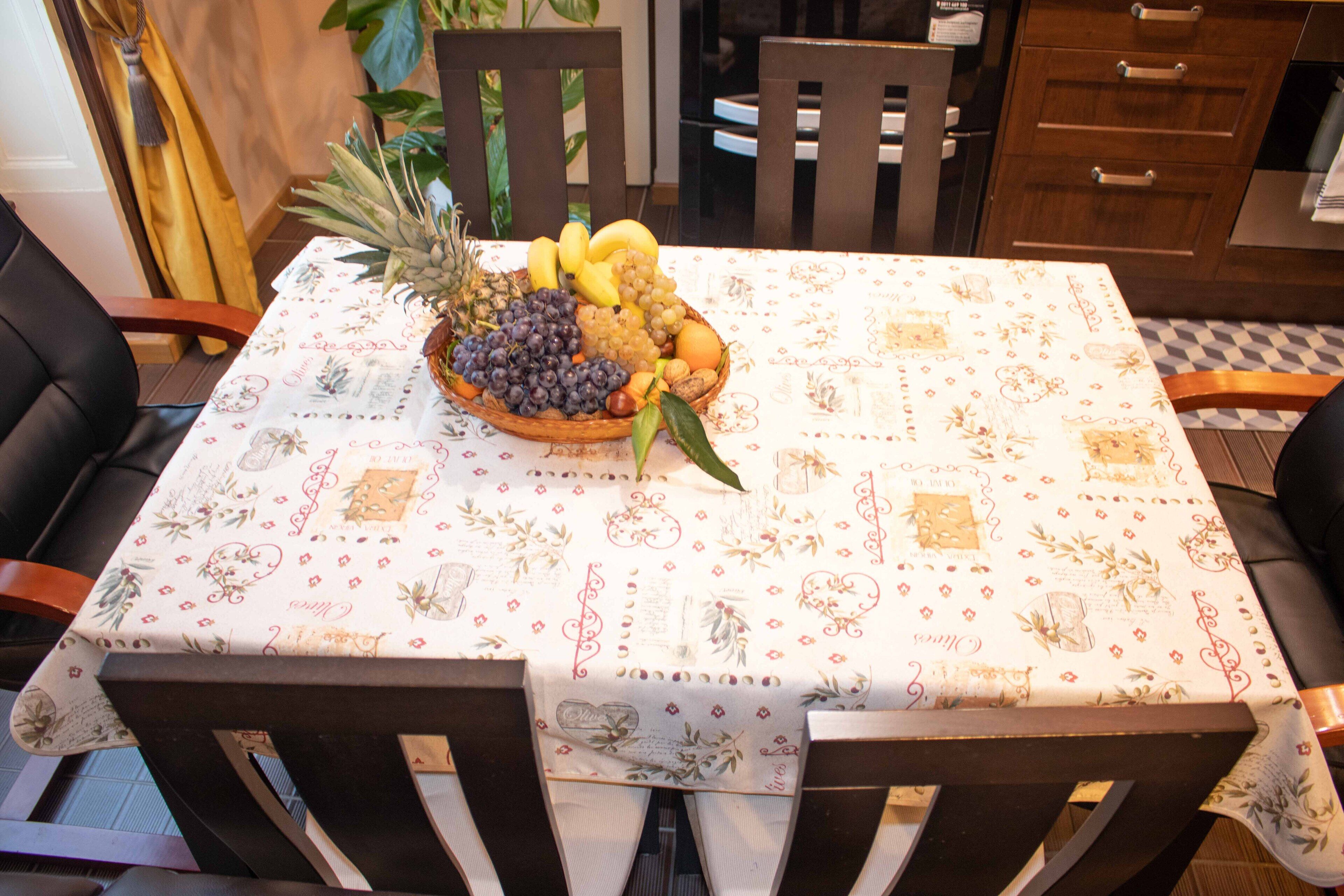 Een eettafel met een tafelkleed met patroon, omringd door houten stoelen.
