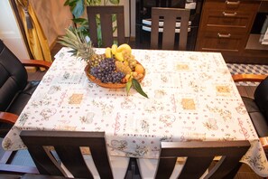 Une table à manger recouverte d’une nappe à motifs, entourée de chaises en bois.